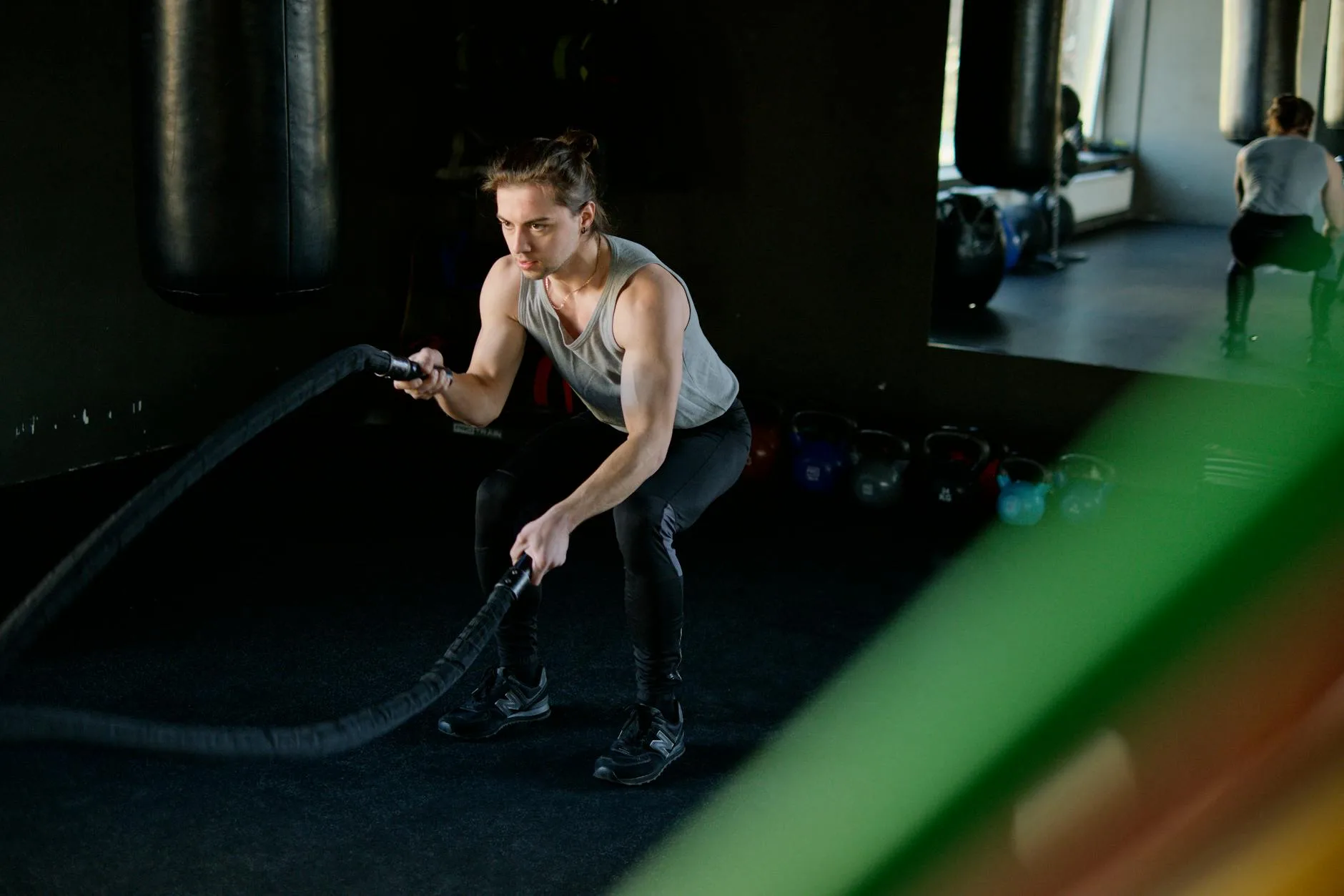 Man engages in an intense battle rope workout in a gym, focusing on fitness and strength.