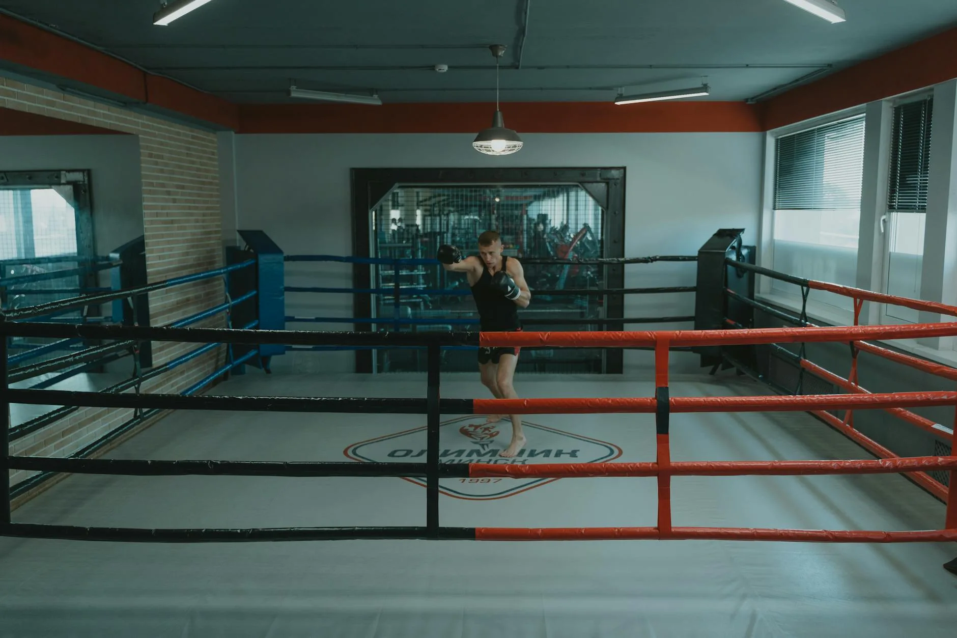 A professional boxer training alone in a well-lit boxing gym ring, showcasing focus and strength.