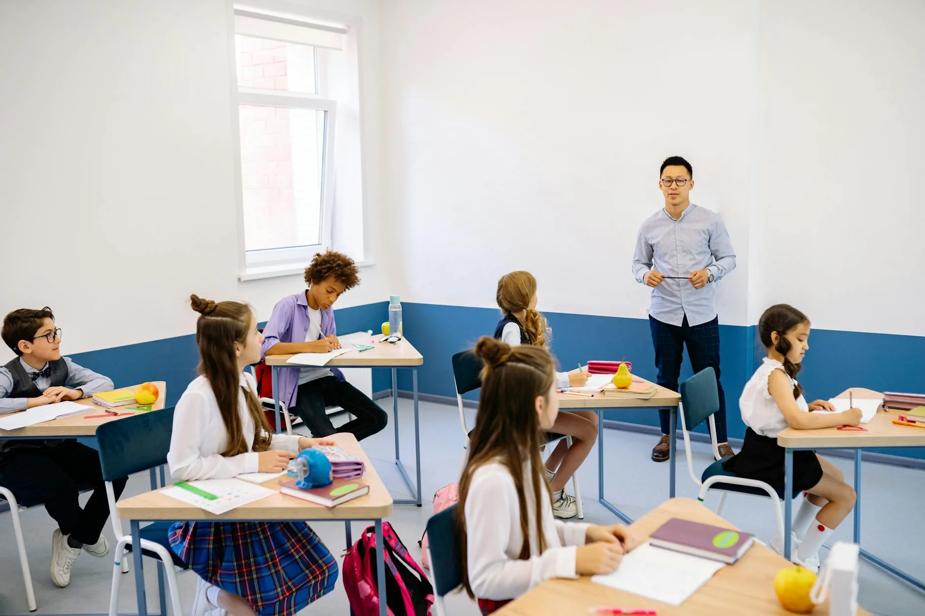 Teacher instructing a diverse group of elementary students in a modern classroom setting.